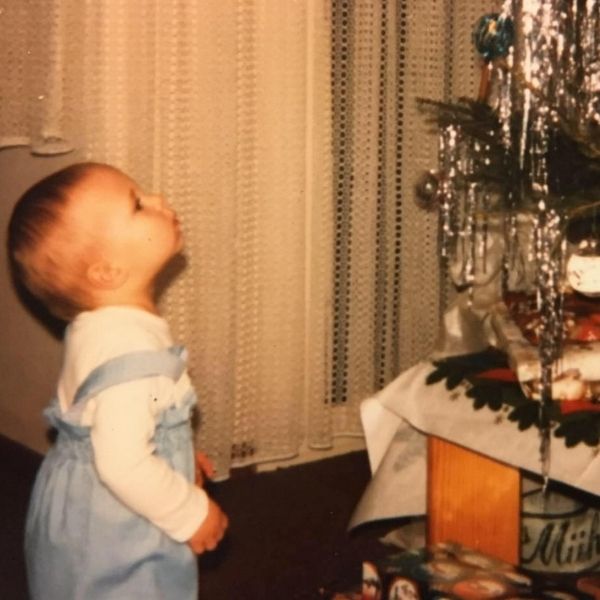 Ein kleines Kind bestaunt einen Weihnachtsbaum.